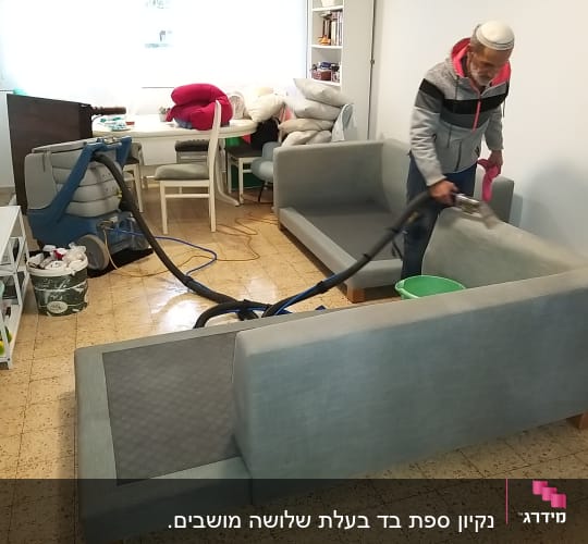 אדם מנקה ספה עם מכונת ניקוי ושואב אבק